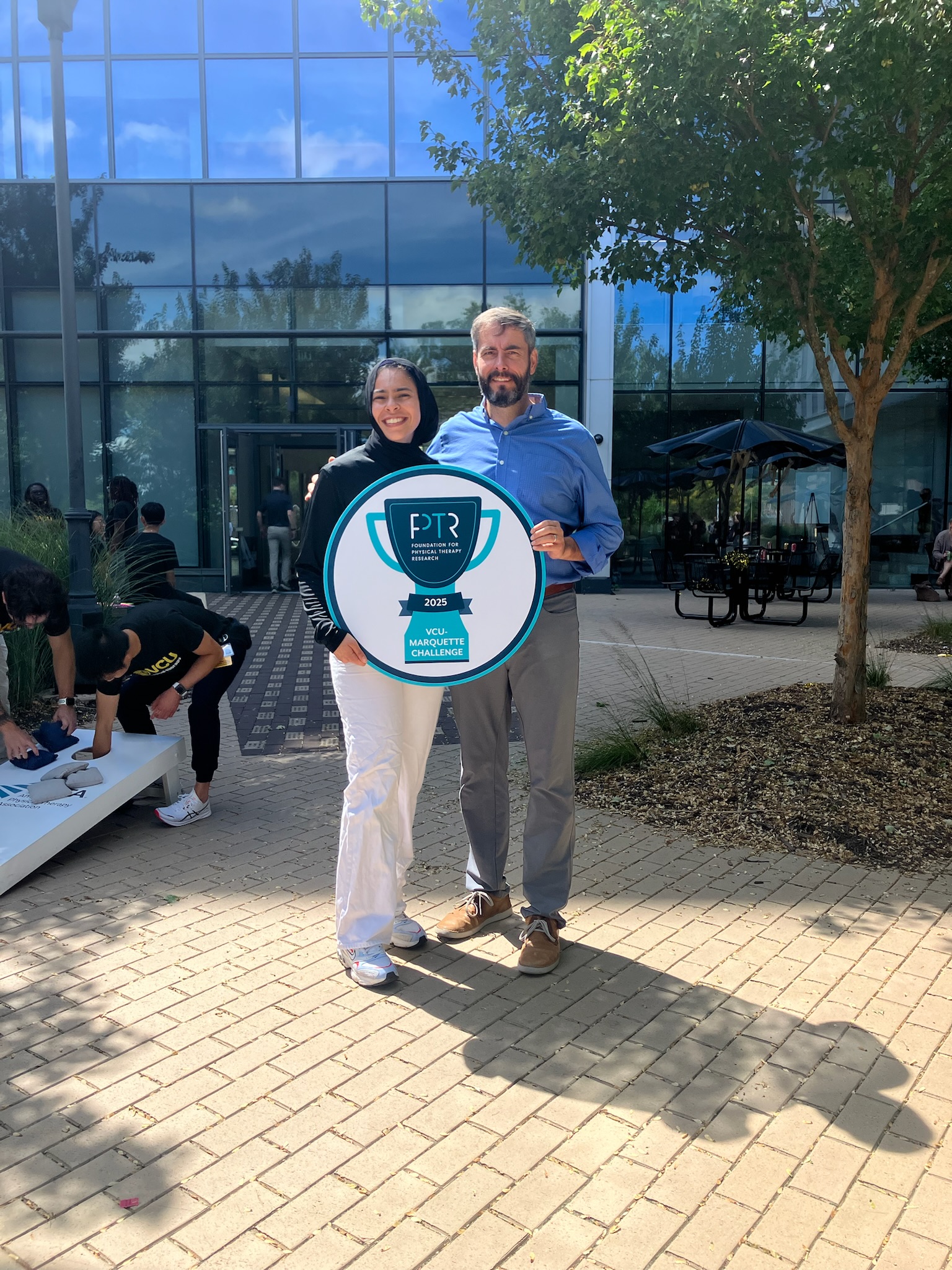 VCU Marquette Challenge trophy held by student and PT professor