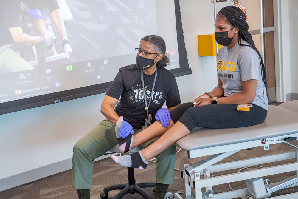 Cheryl Ford-Smith, D.P.T., demonstrates a reflexology exam over Zoom on Kaylah Beharrie, a second-year VCU physical therapy student and 2019 Summer Academic Enrichment Program graduate, in a classroom at VCU College of Health Professions. (Tom Kojcsich, University Relations)